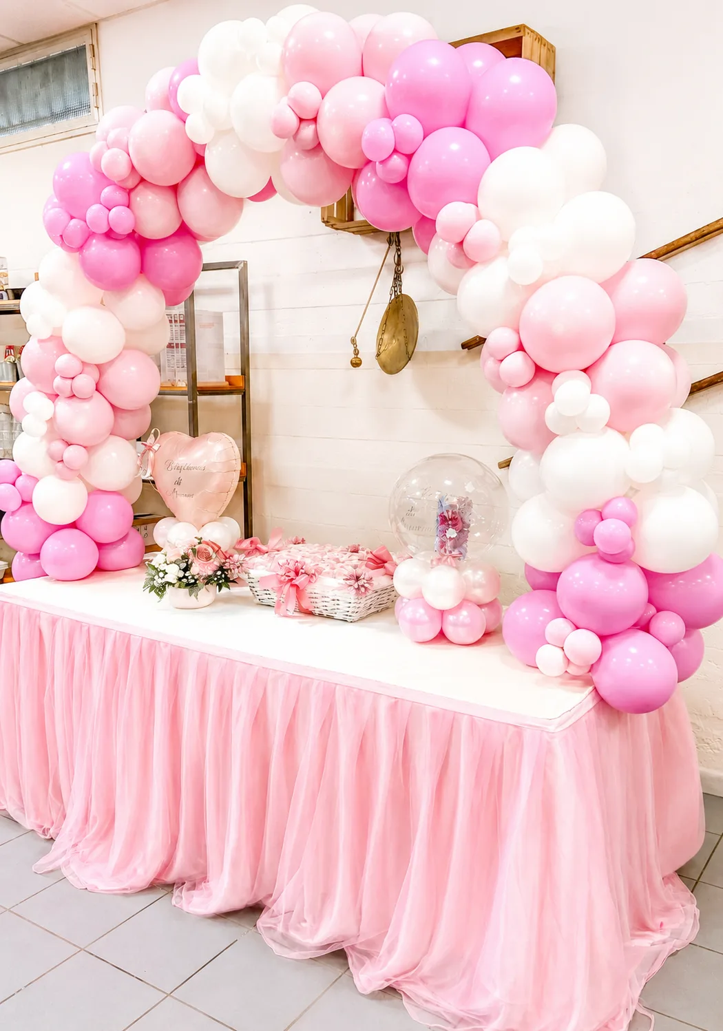 Arche de ballons rose et blanc au-dessus d'une table nappée de tulle